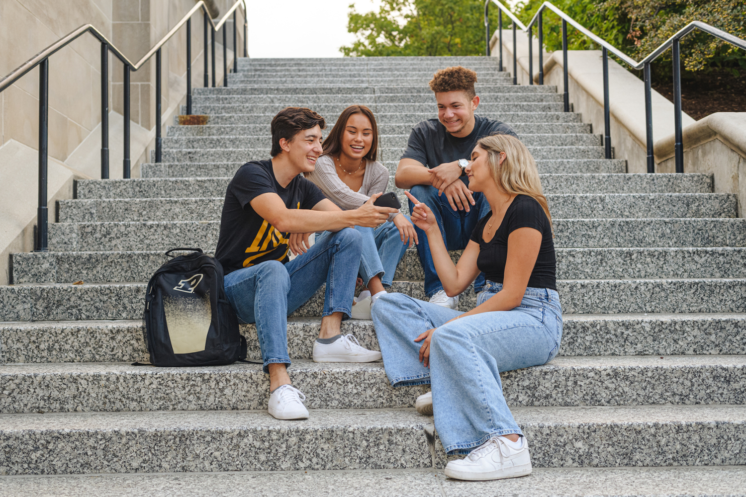 students sit on a staircase talking and laughing