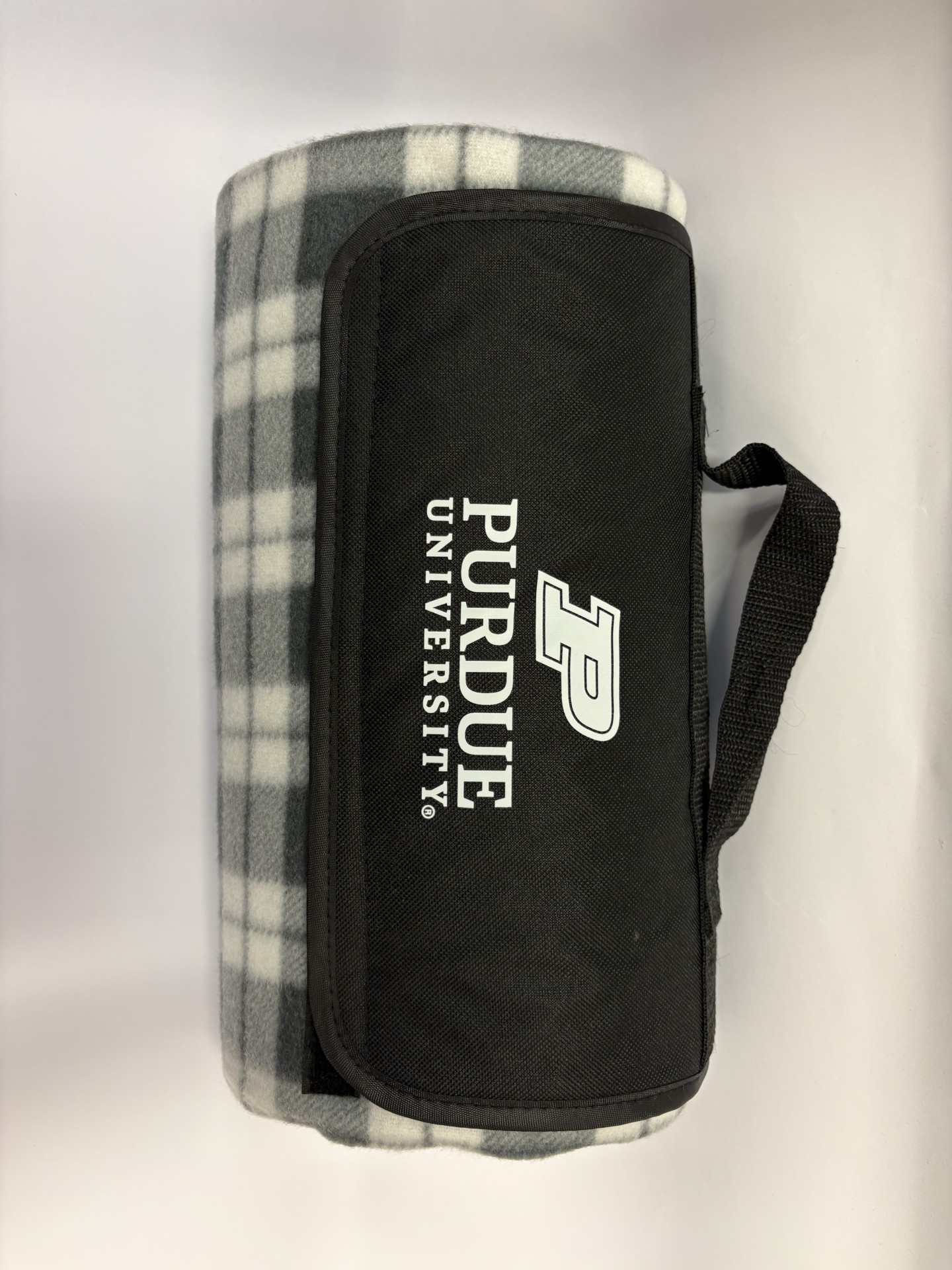 picture of grey/cream plaid blanket with flap saying Purdue University