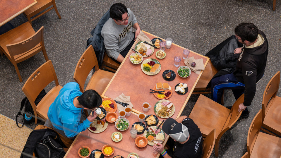An overhead view of students at a table eating a meal together.