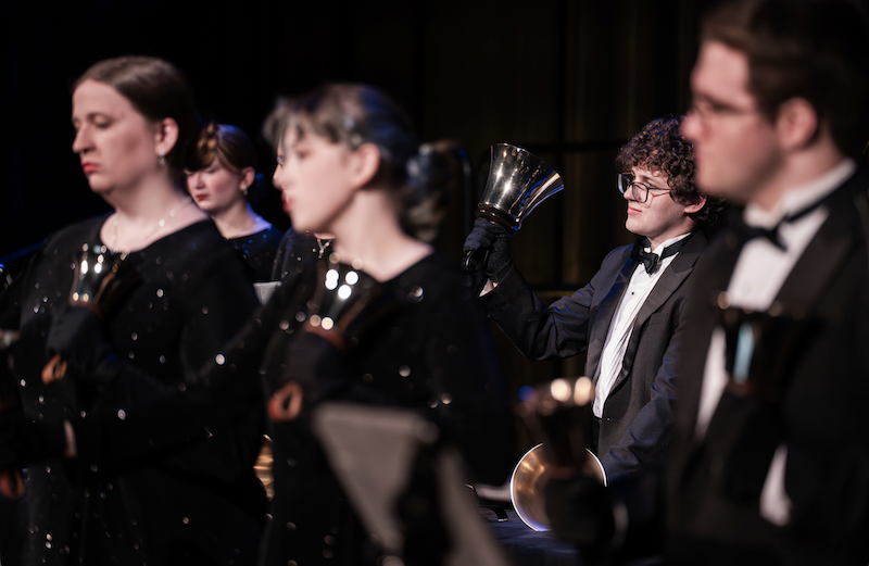 Group of students performing on stage with hand bells
