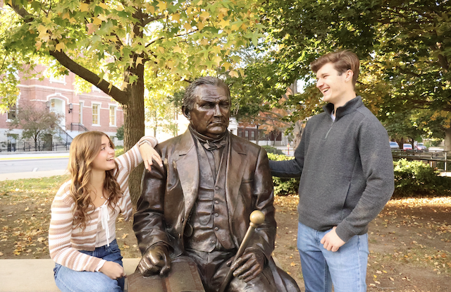 Two students sitting with John Purdue statue