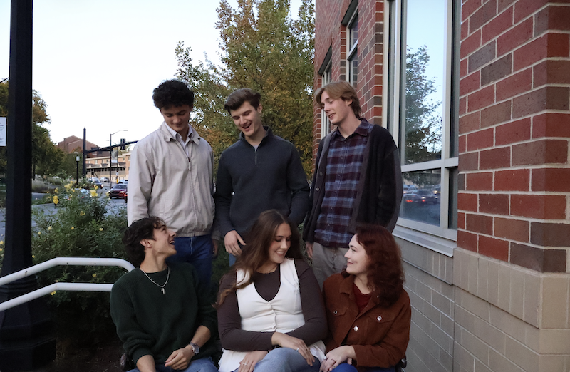 Group of students sitting and standing near a bench