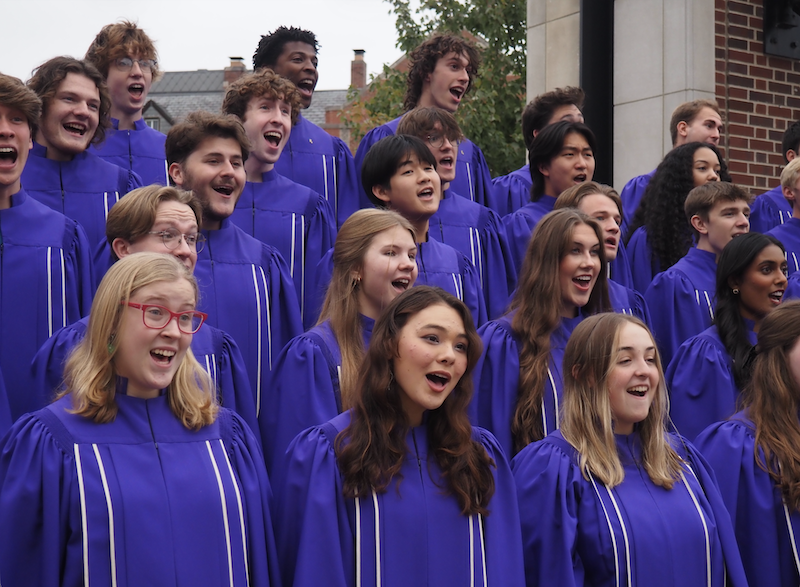 Group of students performing a song together in front of Purdue Memorial Union arch