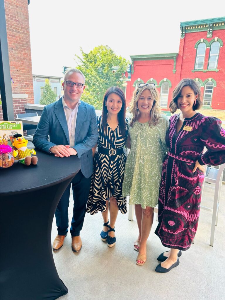 Four people posing together on an outdoor patio at an event