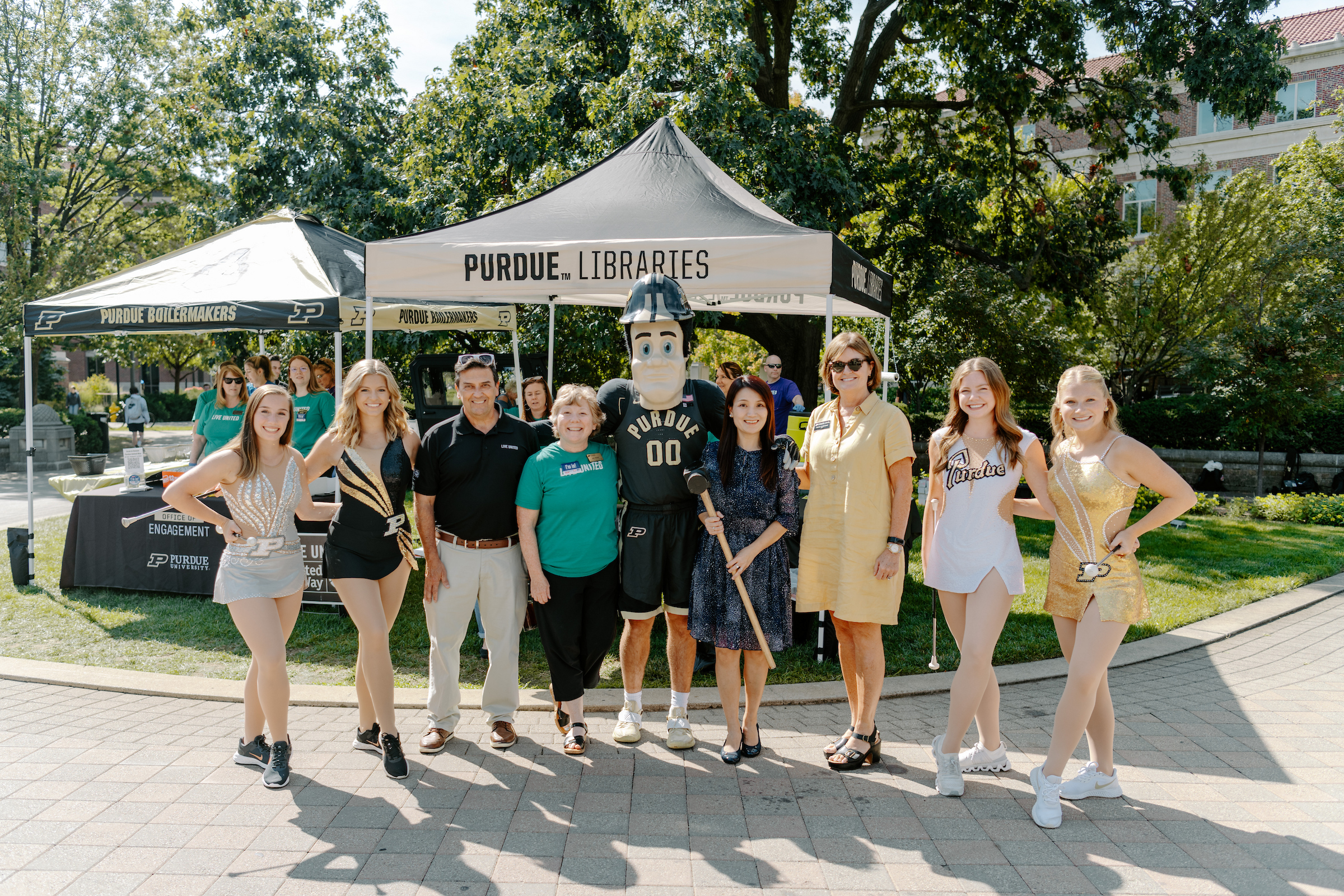 Purdue mascot and twirlers posing with staff at an outdoor event