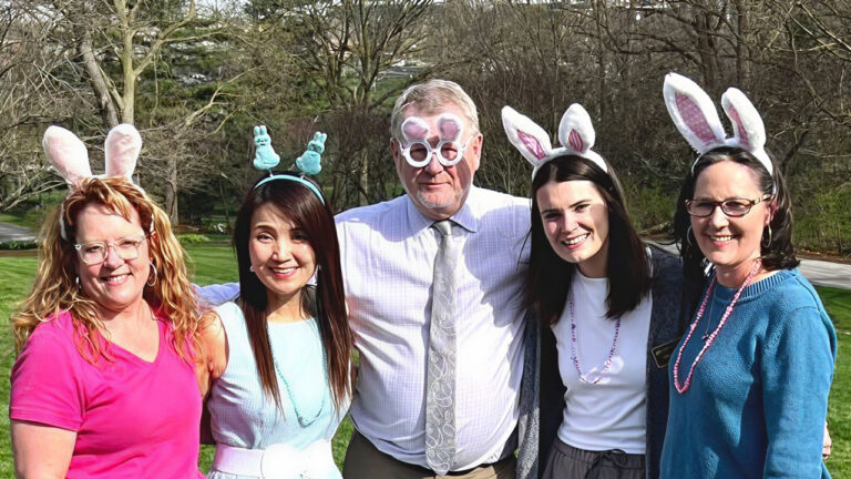 Five people wearing bunny ears posing together at an outdoor event