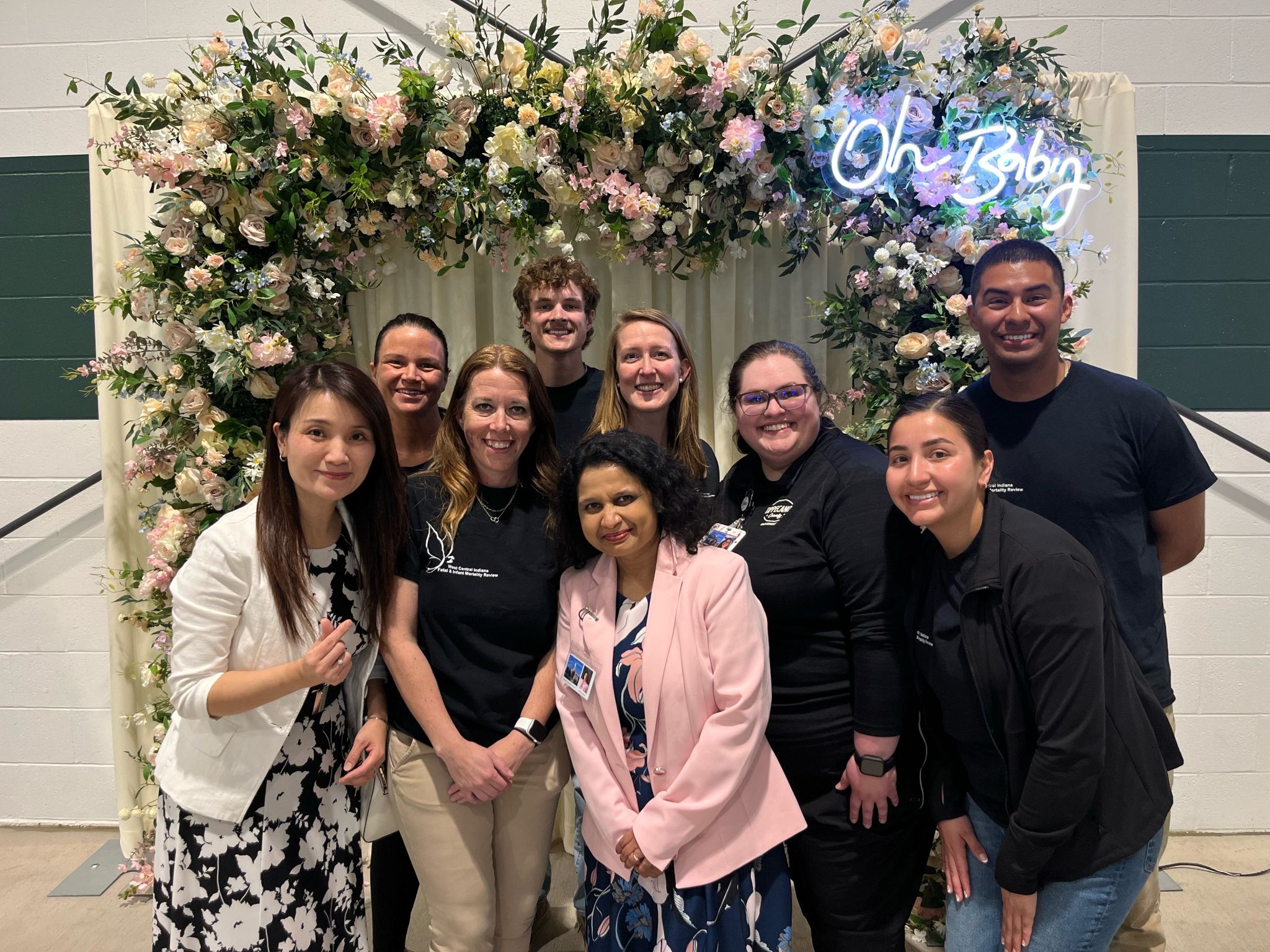 A group of colleagues posing in front of floral decor