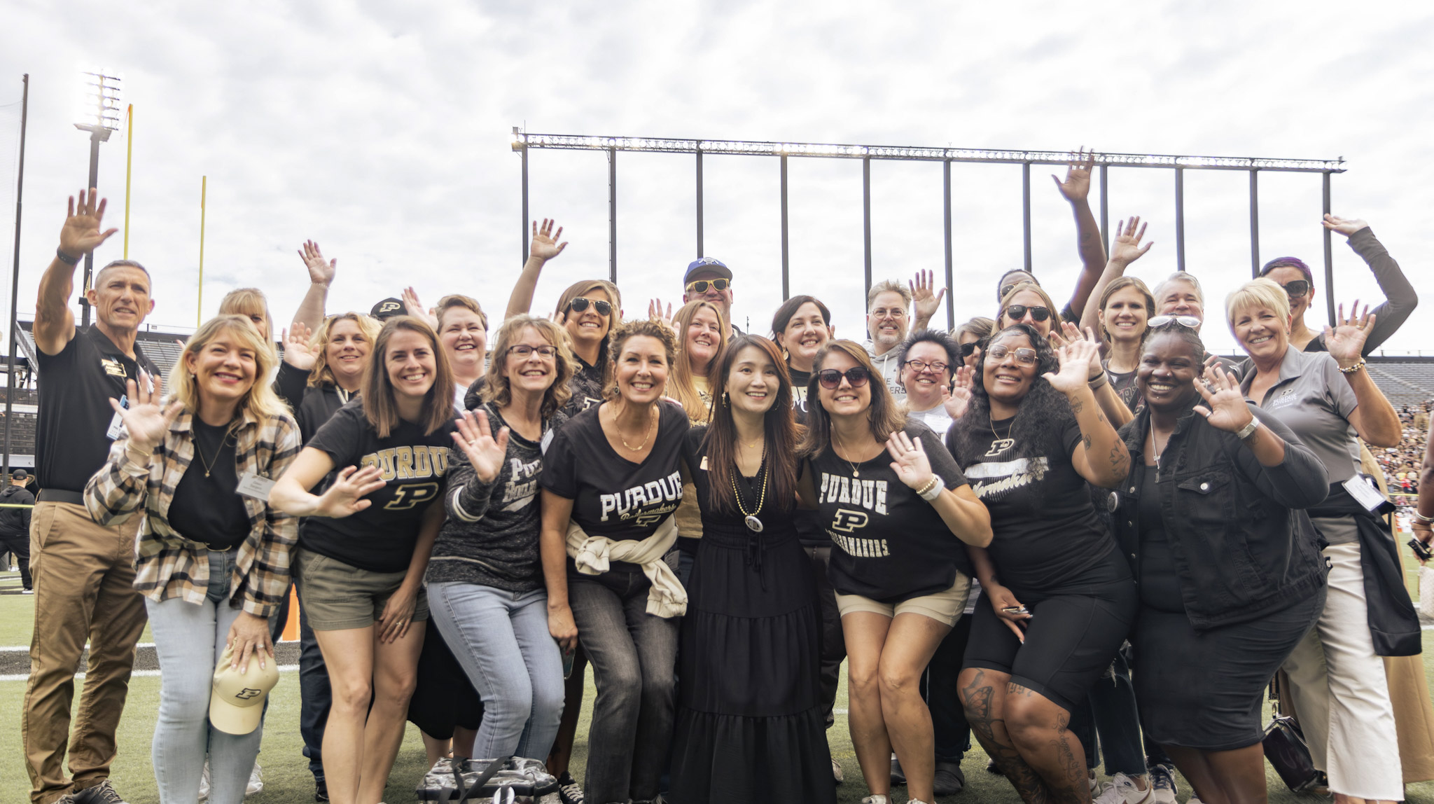 University staff and supporters posing together on a football field