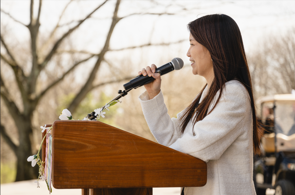 Side profile of a woman addressing an audience outdoors