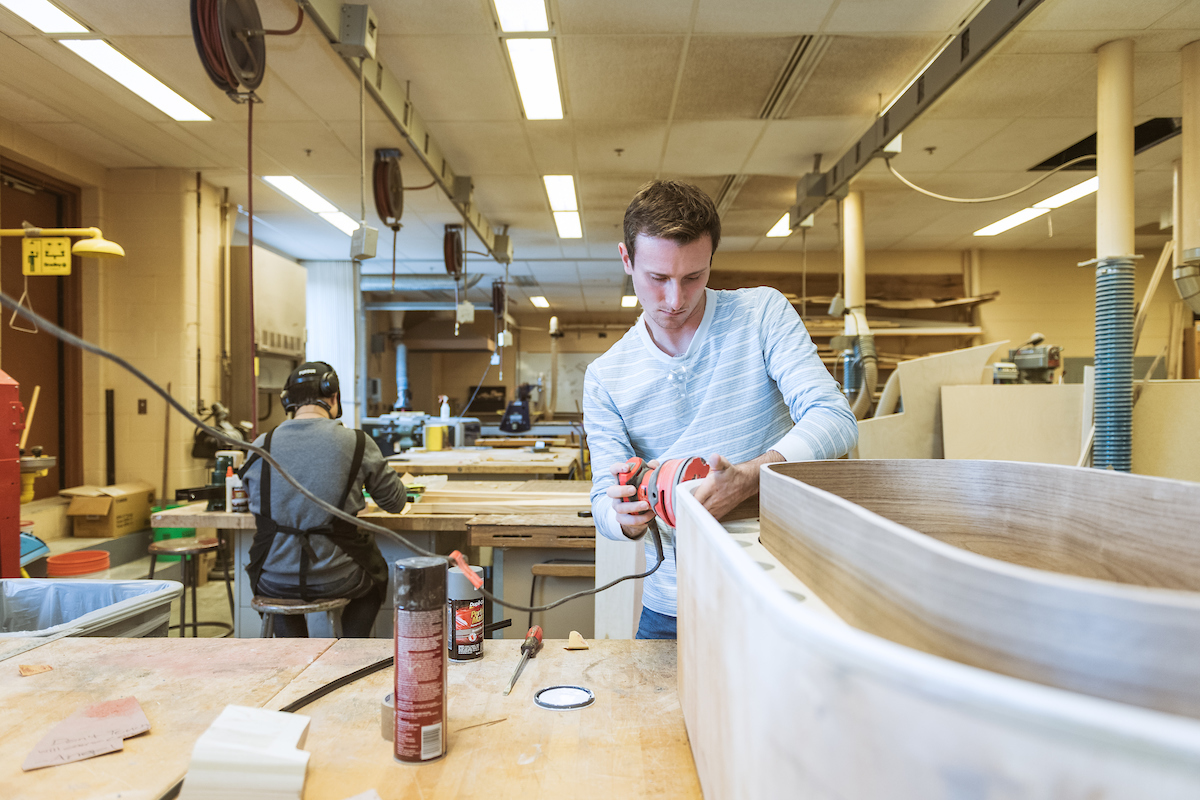 Pictured: student working with wood and a power sander in a purdue classroom lab