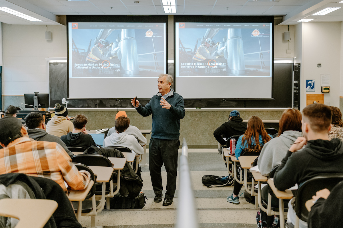 Pictured: purdue faculty member walks down classroom aisle during lecture