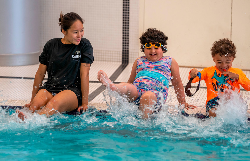 Instructor teaching children how to kick in the water