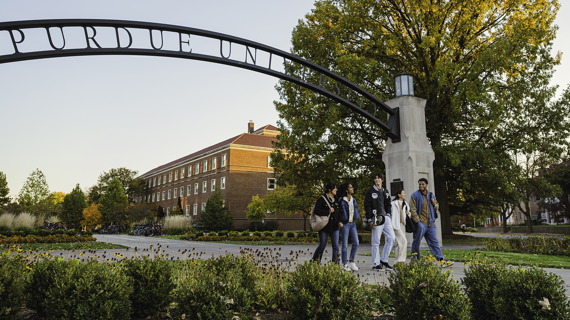 A group of students walk below Purdue's Gateway to the Future Arch on an early fall day