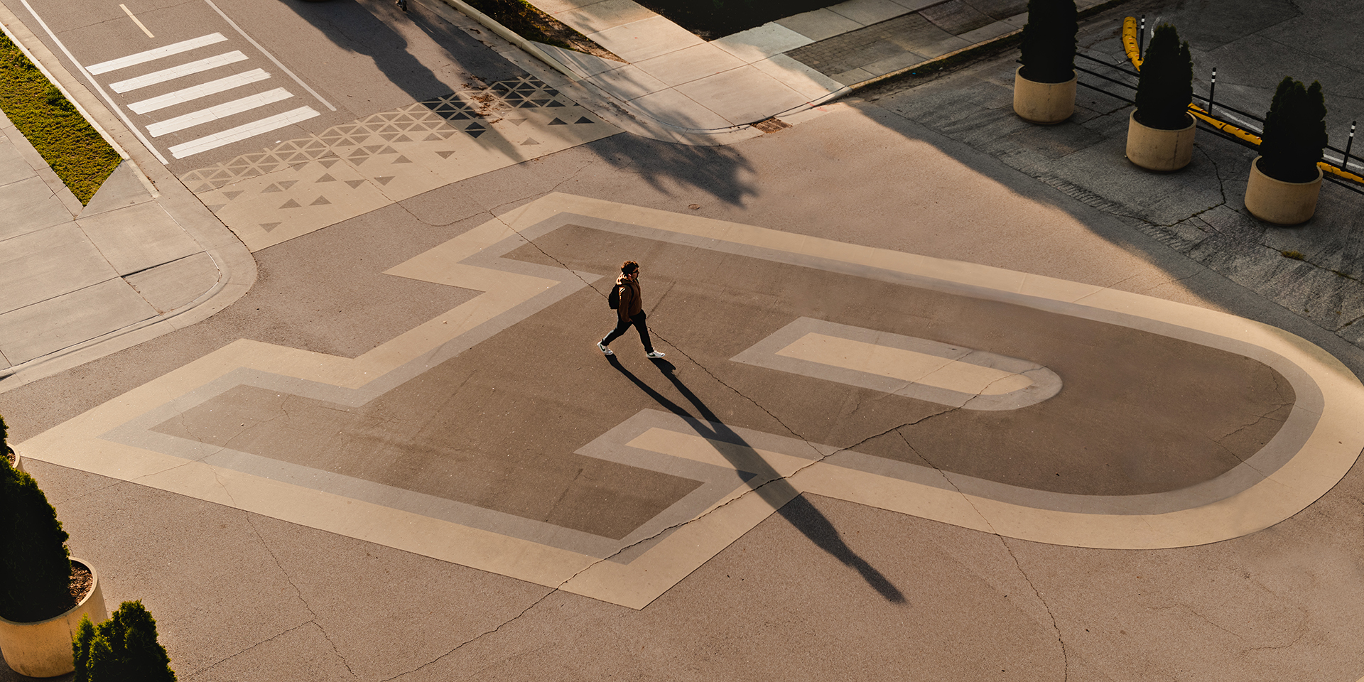 A student walks over Purdue's Motion P painted across Third Street on the West Lafayette campus