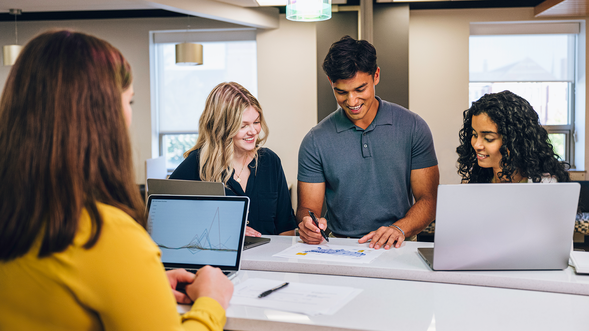 Students gathered around an assignment while one student takes notes.