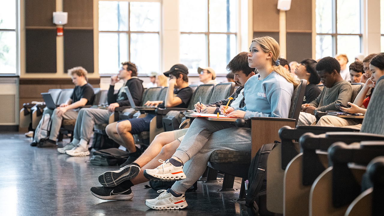 Several students in a classroom taking notes