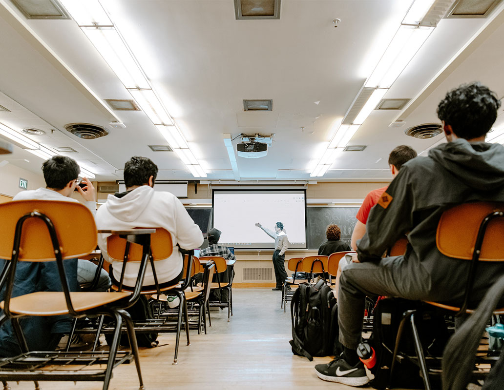 A shot of a classroom full of students in desks from behine