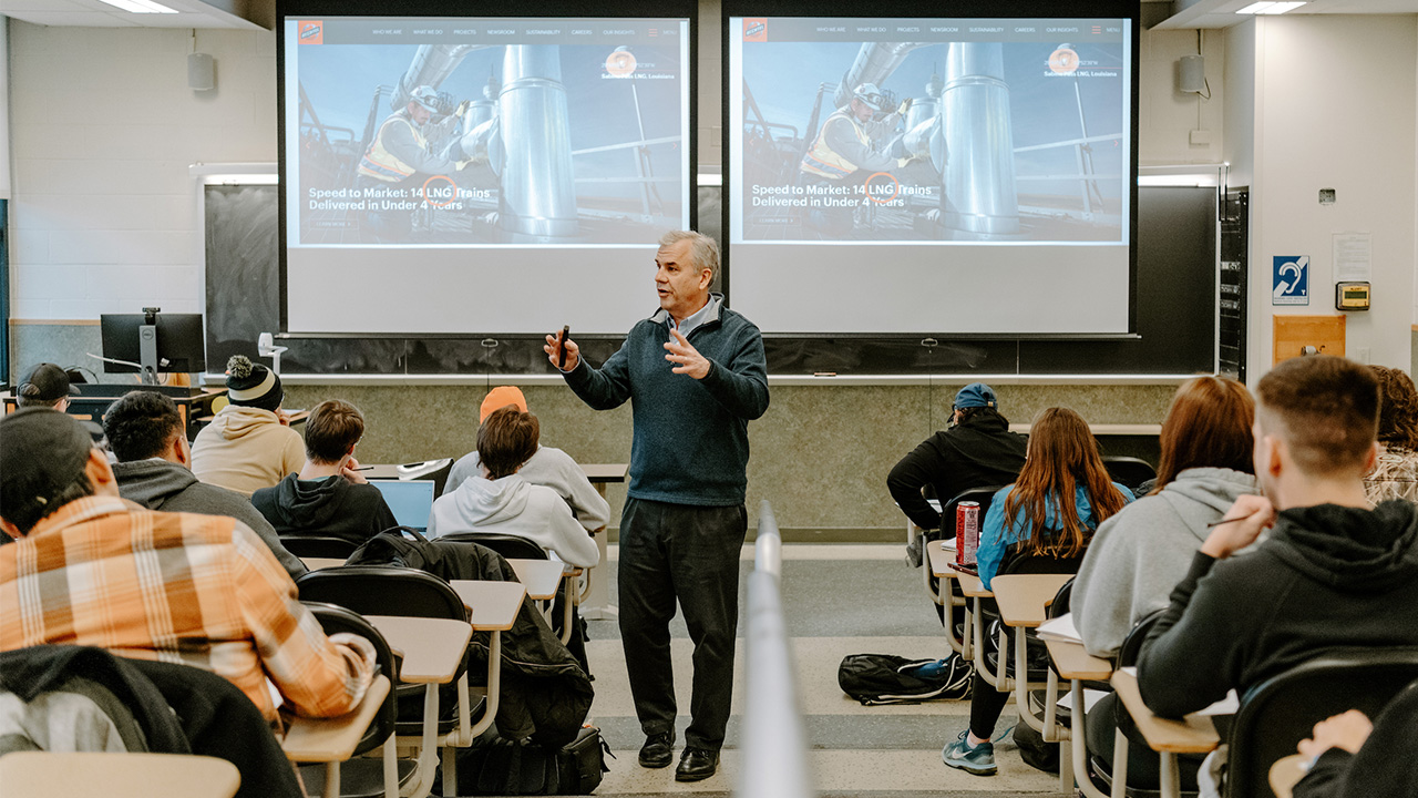 man giving lecture to full auditorium of students