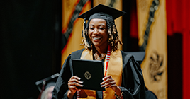 Purdue graduate holding degree at commencement