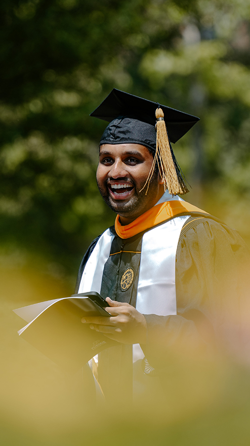 A student smiles walking through the commencment procession