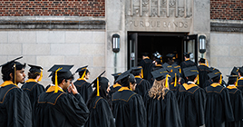 Graduates walk into Elliott Hall for commencement