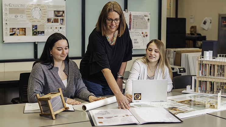 An instructor mentors interior architecture students in a classroom