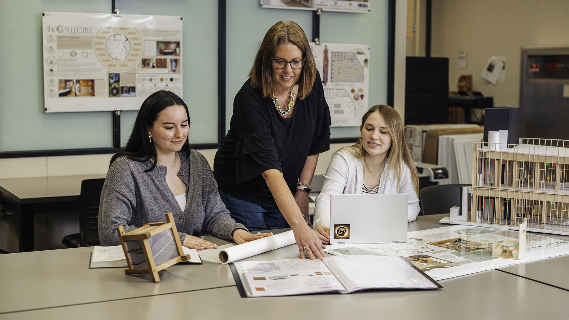 An instructor mentors interior architecture students in a classroom