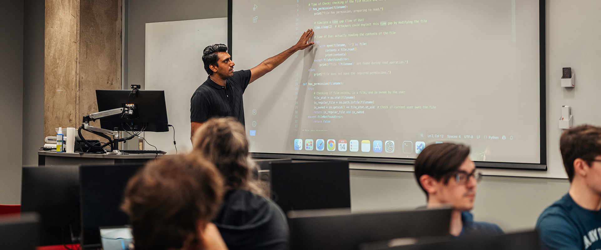 Instructor pointing to a screen in front of a classroom of students