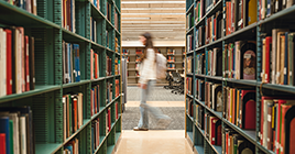 A student walks past the stacks in the library