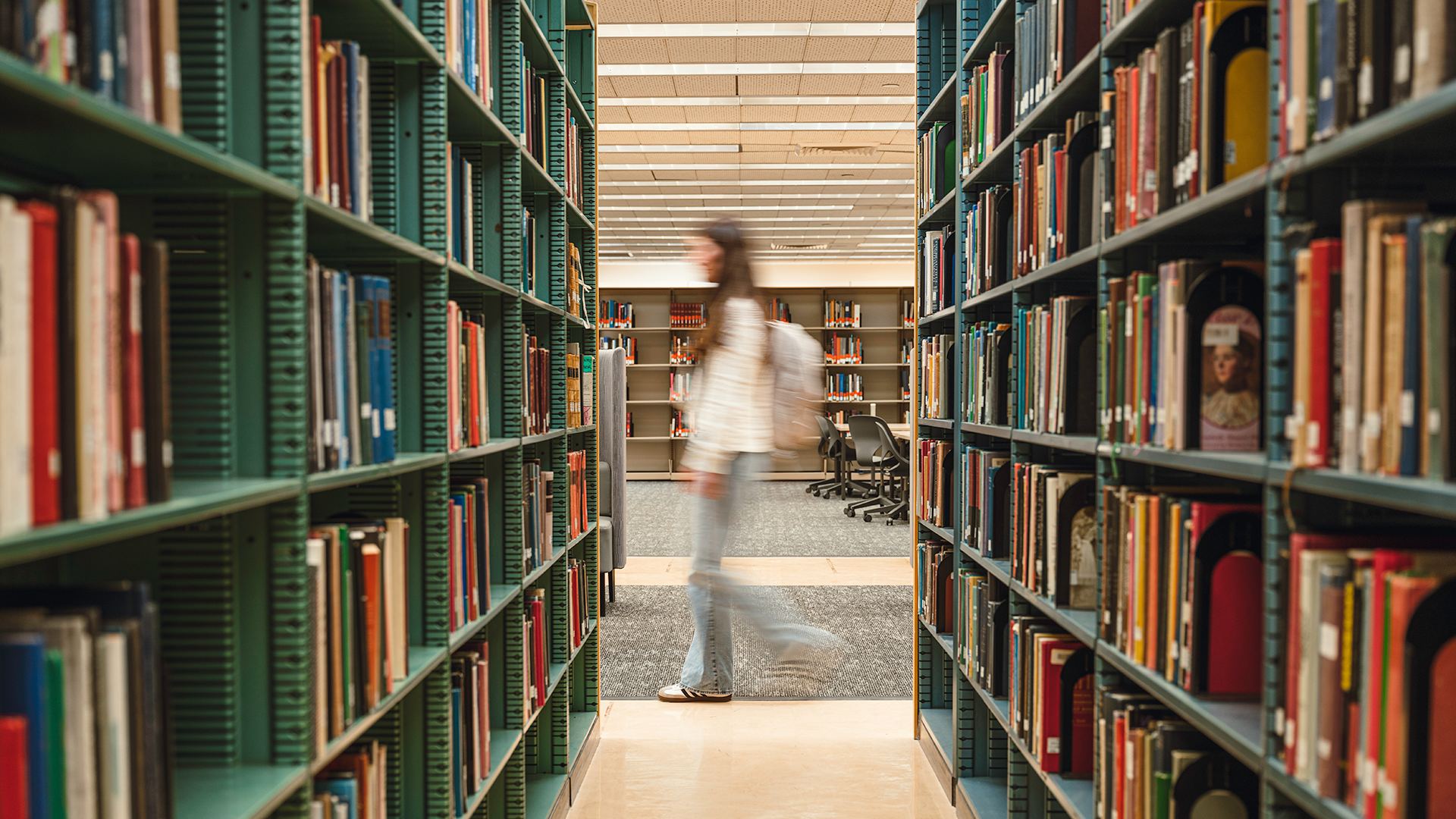 Student walking next to shelves of books