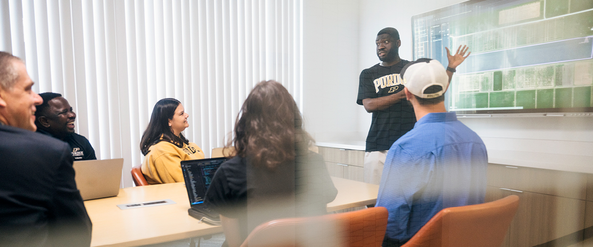 Student presenting at a screen in a meeting room
