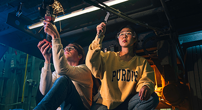 Two students working on mechanical engineering in a dark lab