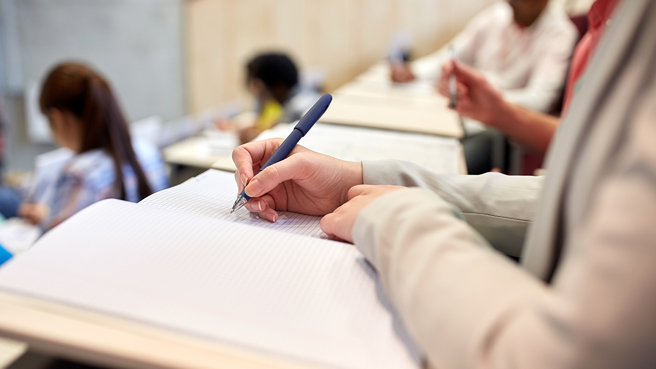 Students take an exam in a theater style classroom