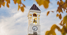 The top of the Purdue Bell Tower through leaves on a fall day