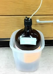 Four liter brown glass HPLC waste collection container with properly modified cap with filter and hose.