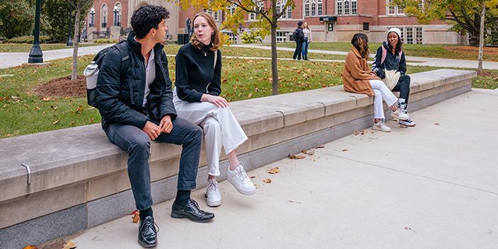 Students sitting while conversing on campus