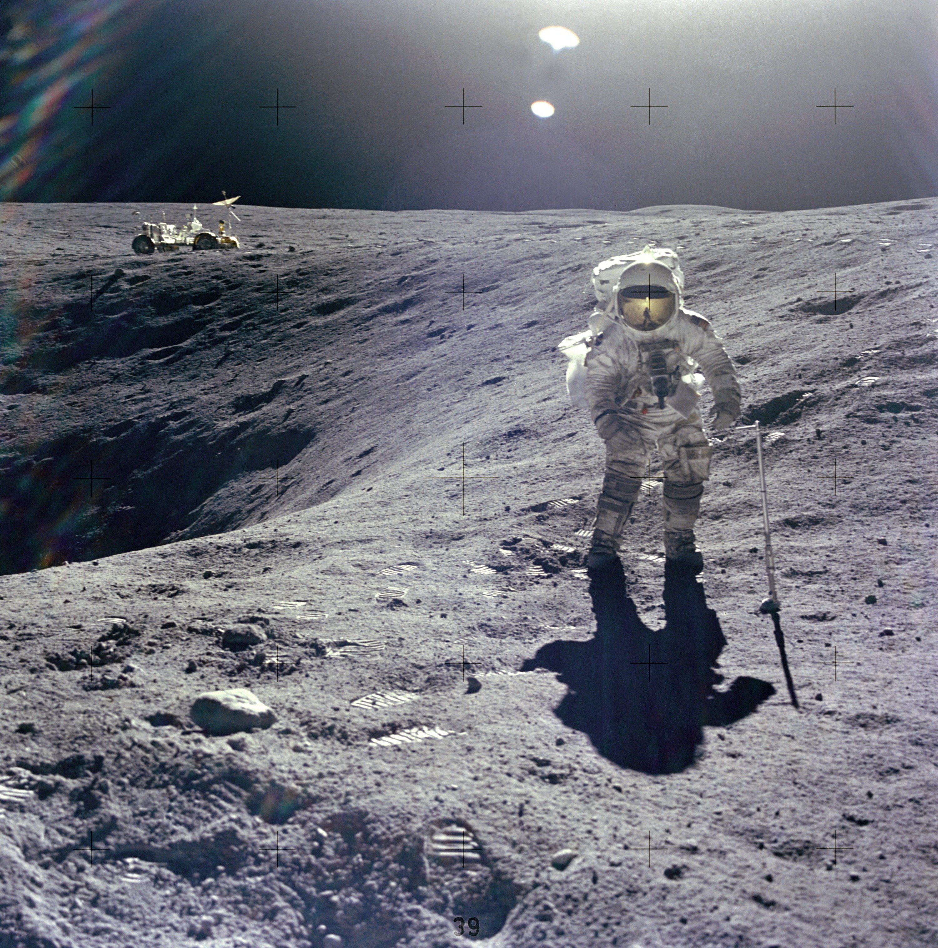 Astronaut and moon rover next to crater on the moon