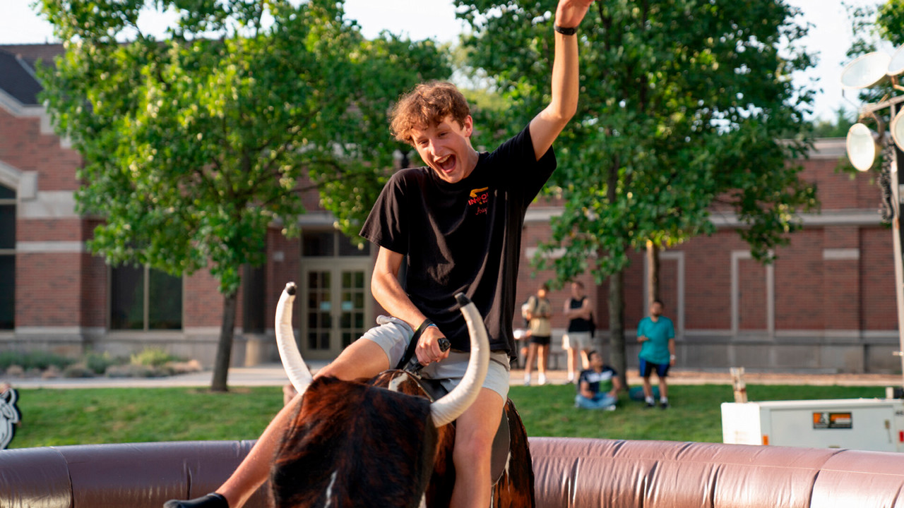 Student rides mechanical bull during PSUB's Wild West Fest.