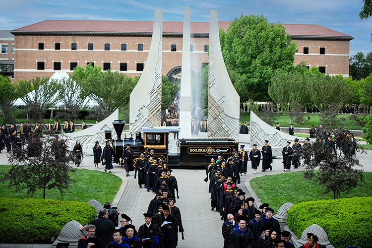 Graduating students celebrate their achievements as they walk past the iconic Class of 1939 Water Sculpture.