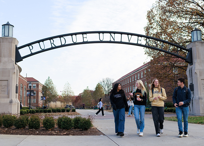 students walking under the Purdue arch