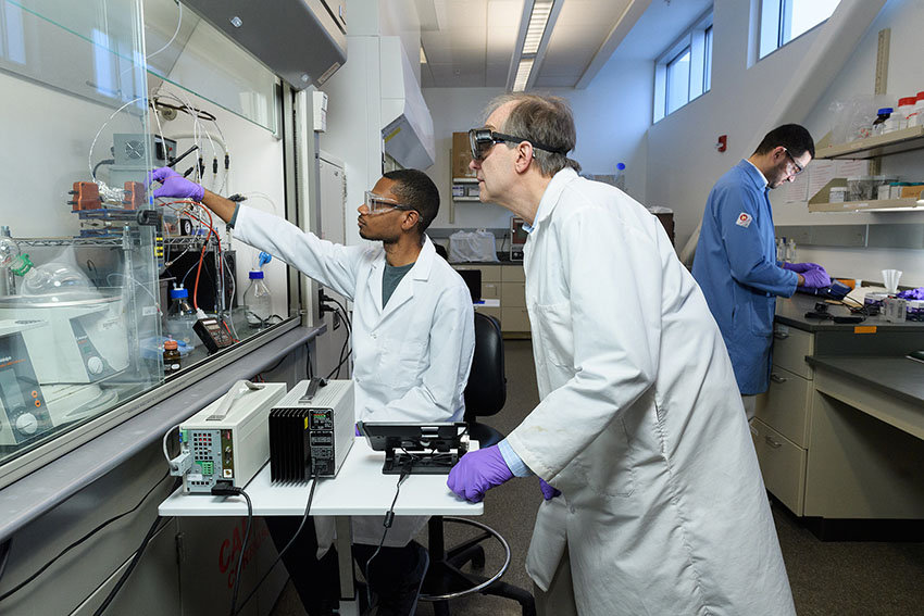 Chemistry professor David Thompson and his team are scaling up the first continuous manufacturing process for an anti-cancer agent. Also pictured are graduate students Jaron Mackey (left) and Ahmed Mufti (right).