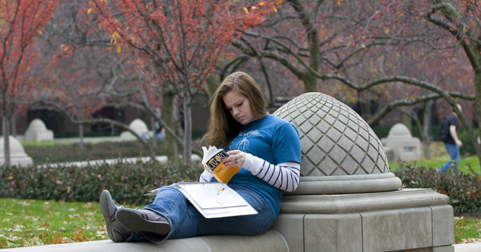Student sitting outside doing research.