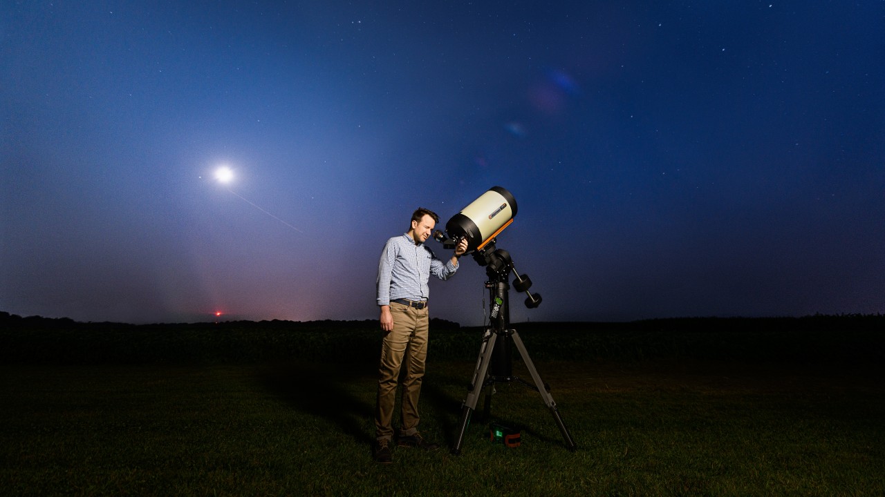 A researcher looks through a telescope in a field