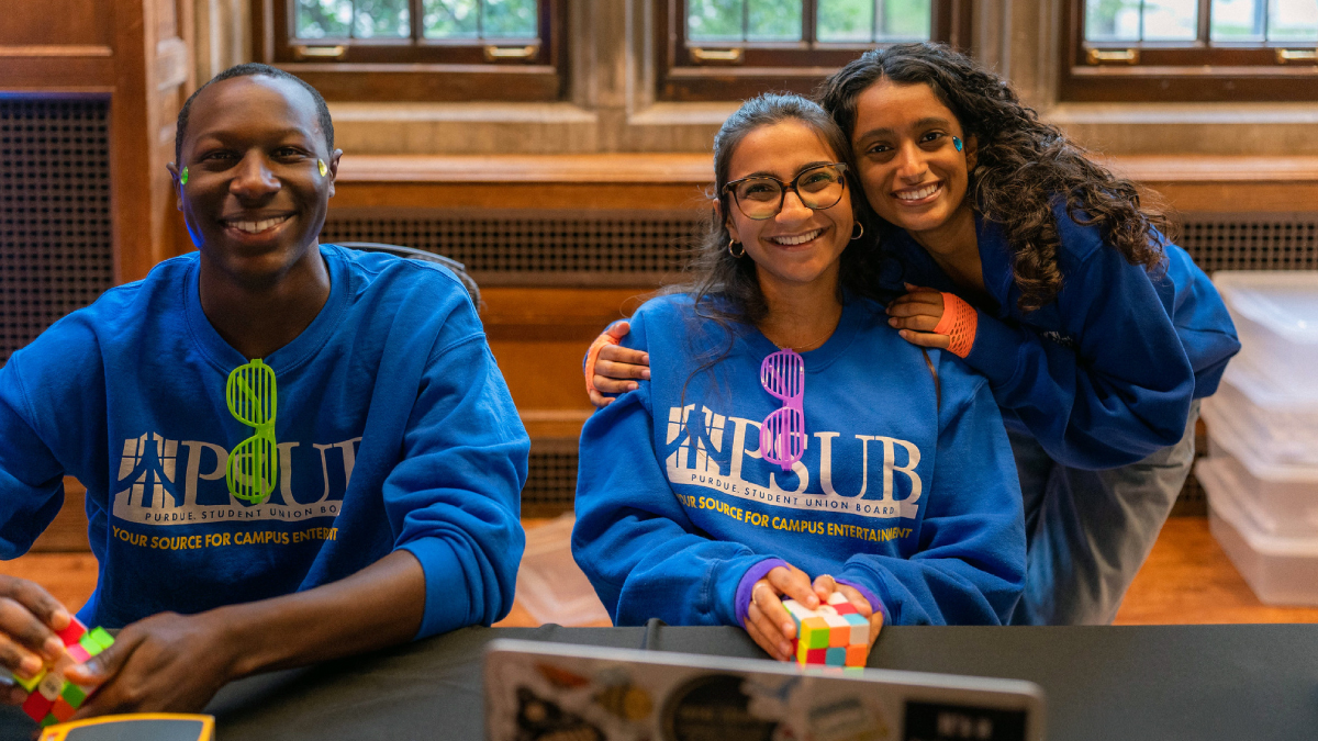 A small group of people wearing PSUB sweatshirts sitting at a table during an event.