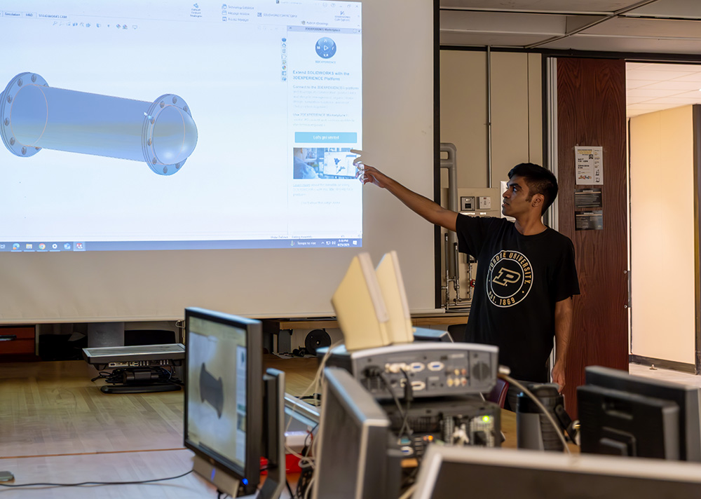 Member of BoilerSubs looking at part on laptop.