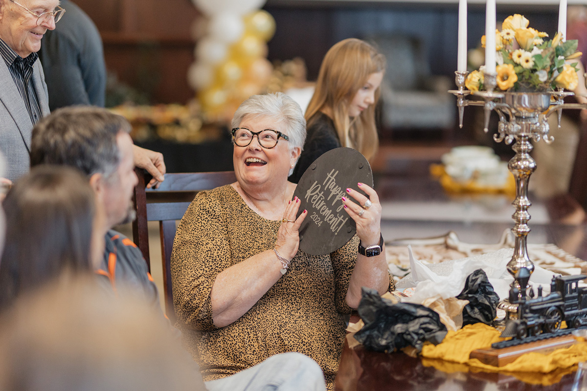 Barb Frazee holding a 'Happy Retirement' plaque at her retirement party.