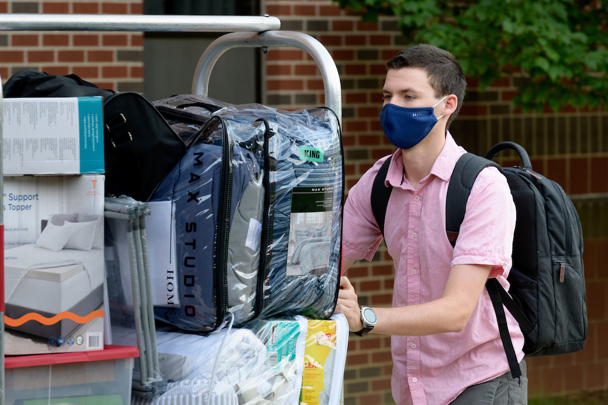 Student pushes cart full of personal items to move into dorm