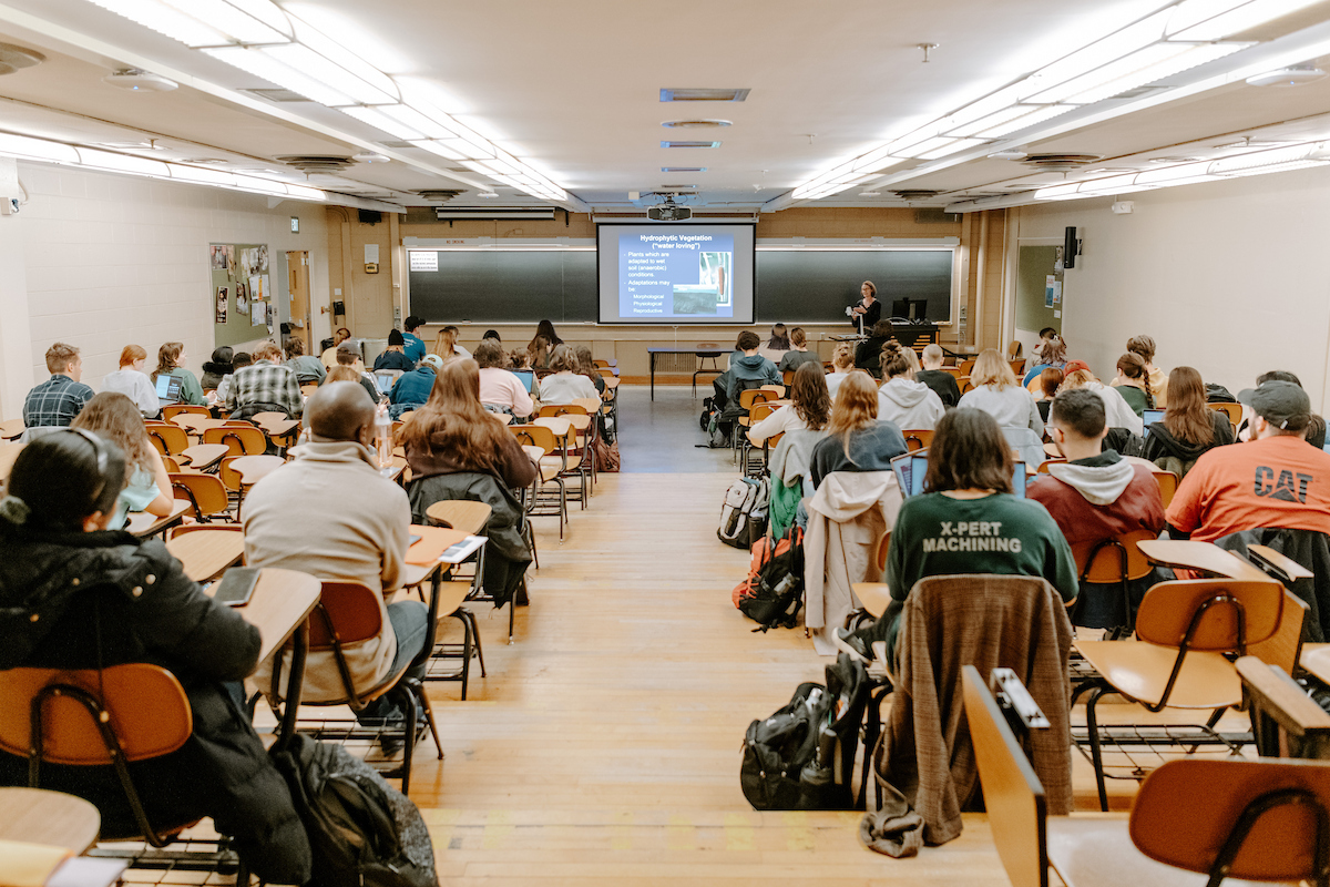 Image showing students gathered around large colorful glowing pole, excitedly yelling