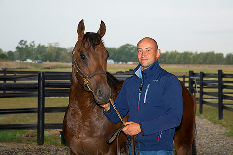 Dr. Tim Gudehus stands next to a brown horse