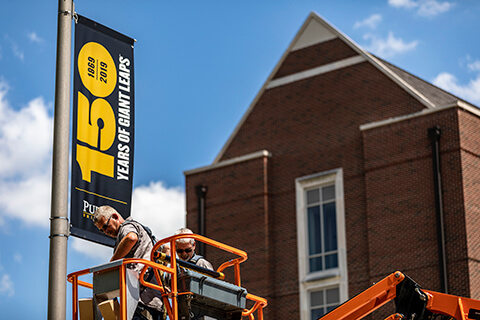 Workers installing Purdue 150th celebration banners
